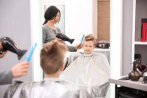 Professional,Female,Hairdresser,Working,With,Little,Boy,In,Salon
