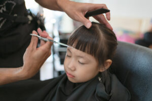 Asian,Little,Girl,Getting,Haircut,By,Hairdresser,At,The,Barbershop.